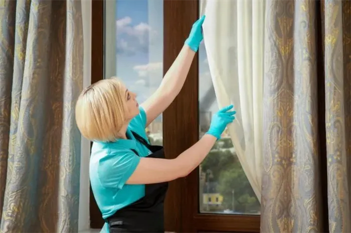 Хозяйка снимает тюль с окна для отбеливания