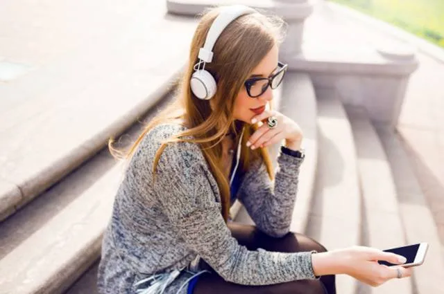Молодая красивая девушка прослушивает музыку через наушники